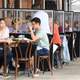 Diners at a sidewalk cafe where clear partitions separate each table